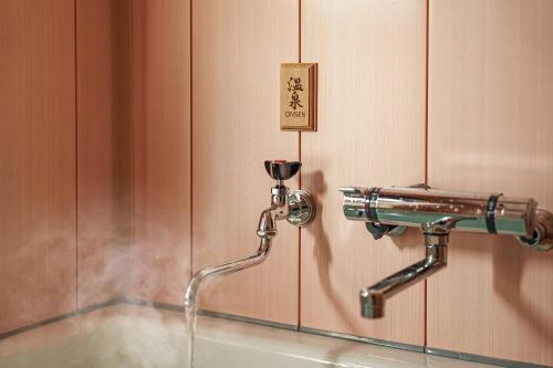 a water faucet on a wall with a water fountain at 夢思苑 別府 in Beppu