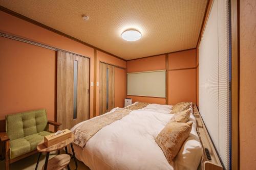 a bedroom with a large bed and a chair at 夢思苑 別府 in Beppu
