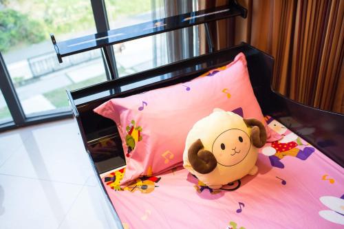 a bed with a stuffed animal on a pink pillow at Diudiu Dang Paternity B&B in Dongshan