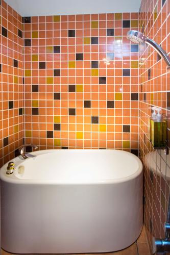 a bath tub in a bathroom with tiles on the wall at Diudiu Dang Paternity B&B in Dongshan