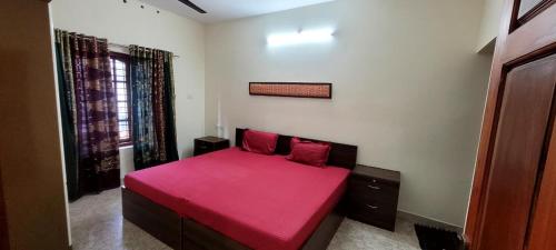 a bedroom with a red bed with a red blanket at K Apartment in Varkala