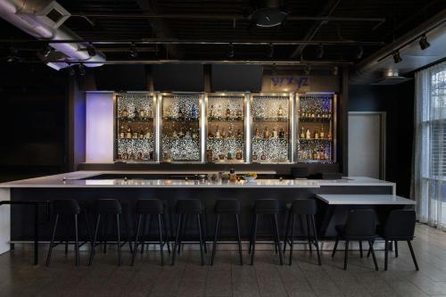 a bar with stools in a room with alcohol bottles at Aloft Houston by the Galleria in Houston