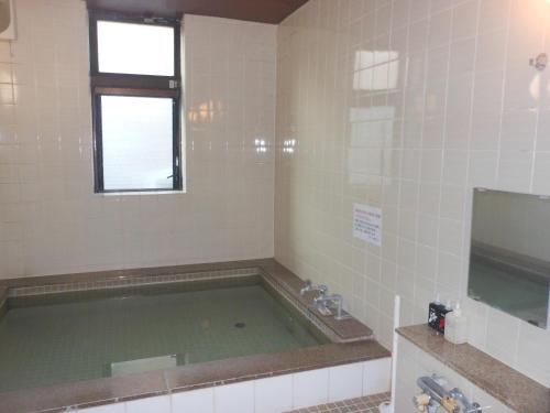 a bathroom with a large tub with a window at Hotel Kimitsu Hills in Kimitsu