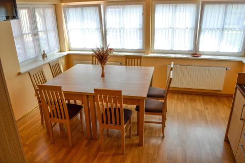 a dining room table and chairs in a room with windows at Vila Liepa in Birštonas