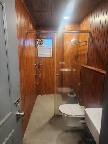 a bathroom with a toilet and a shower with wooden walls at HOTEL N K RESIDENCY in Guwahati