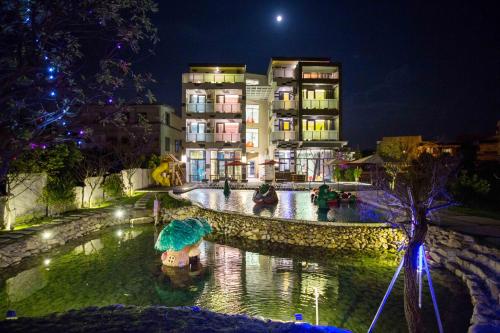 a building at night with a pond with an umbrella at Diudiu Dang Paternity B&B in Dongshan