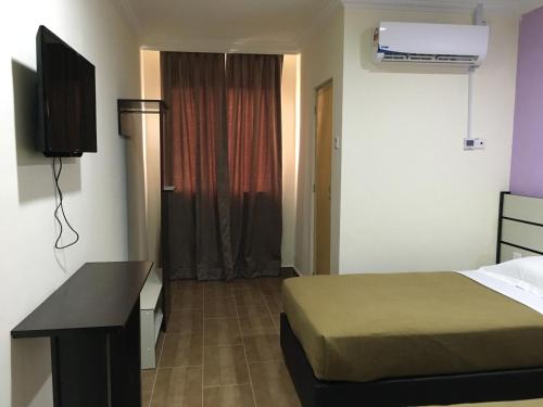 a hotel room with a bed and a desk and a television at Grand Business Hotel in Jertih