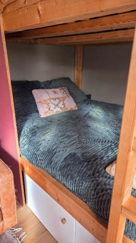 a wooden bunk bed with a black comforter on it at Tinyhouse op de Veluwe, het buitenleven in Oene