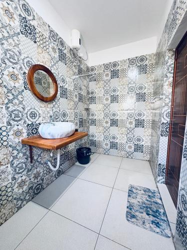 a bathroom with a mirror on a tiled wall at Vrindavan homestay in Munroe Island