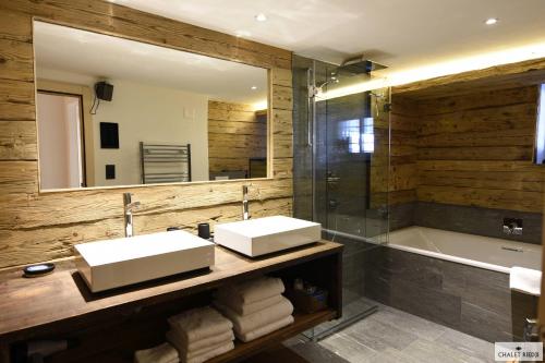 a bathroom with two sinks and a mirror and a tub at Ferienhaus Chalet Riedji in Furna