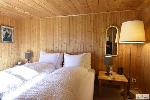 a bedroom with two beds and a lamp and a mirror at Ferienhaus Chalet Riedji in Furna