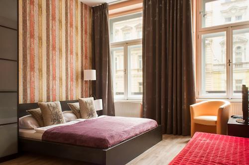 a bedroom with a bed in a room with windows at Royal Court Legerova in Prague