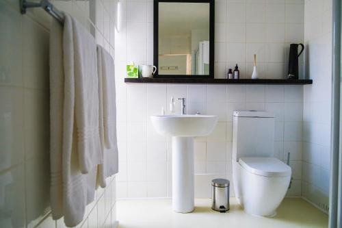 a white bathroom with a sink and a toilet at Agulhas Ocean House in Agulhas