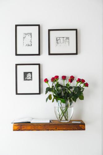 a vase with flowers on a shelf with three framed pictures at Agulhas Ocean House in Agulhas