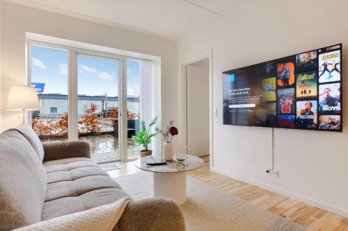 a living room with a couch and a tv on a wall at Fantastisk bolig midt i Odense C in Odense