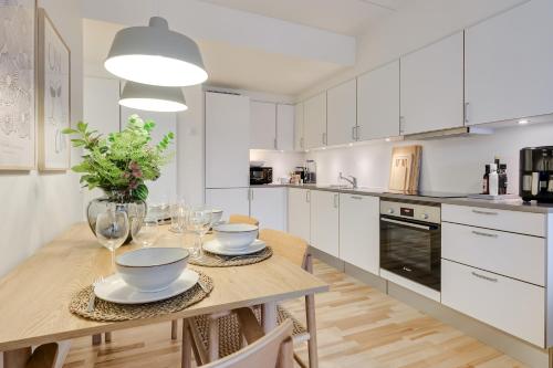 a kitchen with white cabinets and a wooden table at Fantastisk bolig midt i Odense C in Odense