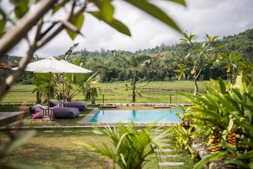 a resort pool with chairs and an umbrella at Blue Garden Yogyakarta in Yogyakarta