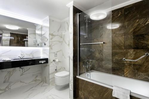 a bathroom with a shower and a toilet and a sink at COSMOPOLITAN Hotel Prague in Prague