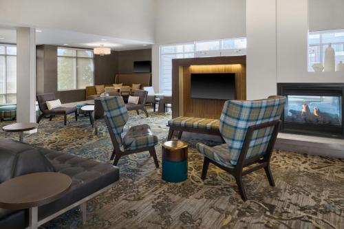 a lobby with chairs and a couch and a fireplace at Residence Inn by Marriott Charlotte Airport in Charlotte