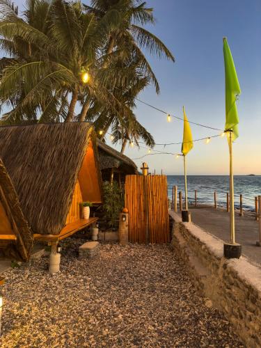 a hut on the beach with a palm tree and the ocean at CocoHaus in Batangas City