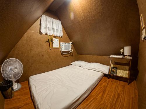a small room with a bed and a fan at CocoHaus in Batangas City
