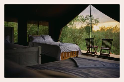 a bedroom with two beds and a window with a chair at NATURE LOVERS ADVENTUREs in Maasai Mara National Reserve