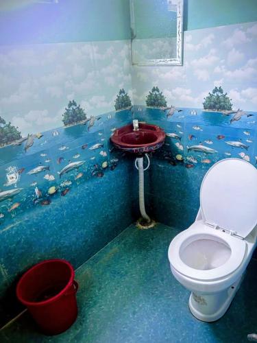 a bathroom with a toilet and a fish painting on the wall at Virasat Guest House in Lucknow