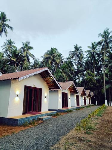 a row of houses with palm trees in the background at Palm Paradise Resort in Revadanda