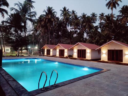 a swimming pool in a resort at night at Palm Paradise Resort in Revadanda