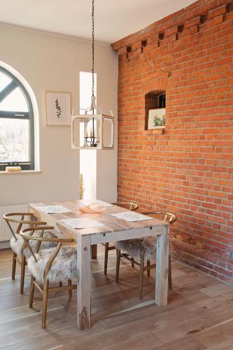 a dining room with a wooden table and a brick wall at Loft Amalia w wieży strażackiej, butikowy, blisko jeziora in Szczecinek