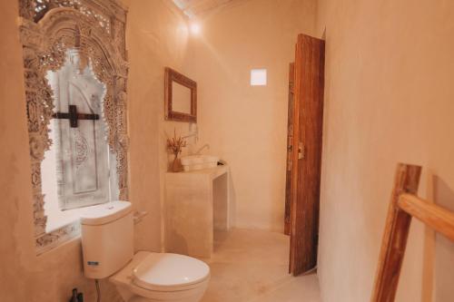a bathroom with a toilet and a wooden door at Romantic private villas Buvillas nusa penida in Nusa Penida