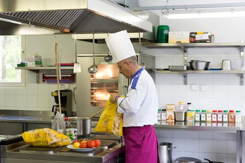a chef is preparing food in a kitchen at Casa di vacanza Giovanibosco in Bosco Gurin