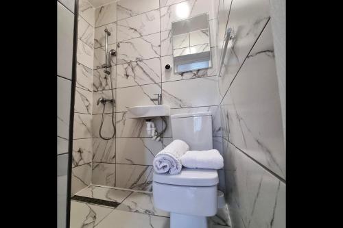 a white bathroom with a toilet and a shower at Peace Guest House in Hoo
