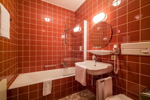 a red tiled bathroom with a sink and a tub at Aparthotel Andreas Hofer in Kufstein