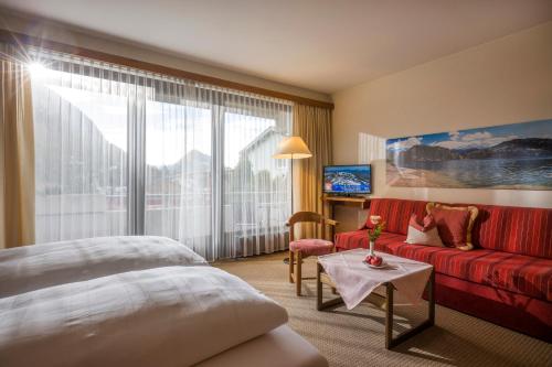 a hotel room with a bed and a red couch at Aparthotel Andreas Hofer in Kufstein