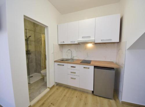 a kitchen with white cabinets and a sink and a shower at Adriatic Guesthouse Balota with Shared Pool in Viganj
