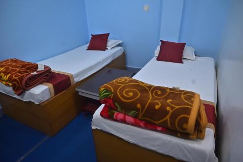 two twin beds in a room with a blue background at 3 Sixty House in Bodh Gaya