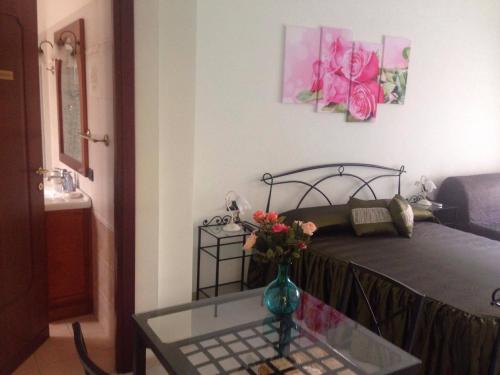 a bedroom with a bed with a vase with flowers on a table at Floreo Guest House in Rome