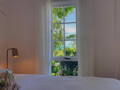 a bedroom with a white bed and a large window at Moana bungalow in Hideaway Bay