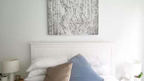 a bedroom with a bed with a painting above it at Stylish Coastal Stay in Cronulla