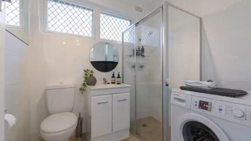 a bathroom with a toilet and a washing machine at Stylish Coastal Stay in Cronulla