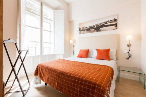 1 dormitorio con 1 cama con manta naranja en Apartamento Trajano, en Sevilla