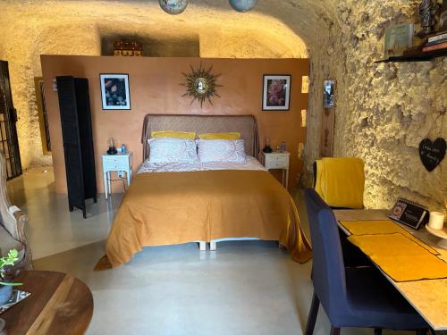 a bedroom with a bed and a table and chairs at Troglodytes "Loire Sauvage" in Rochecorbon