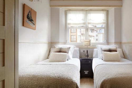 two beds in a white room with a window at Val de Ruda Luxe 42 by FeelFree Rentals in Baqueira-Beret