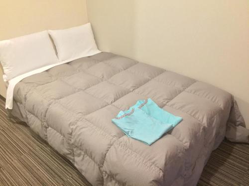 a bed in a room with a blue bag on it at Hotel Niihama Hills Prince House in Niihama