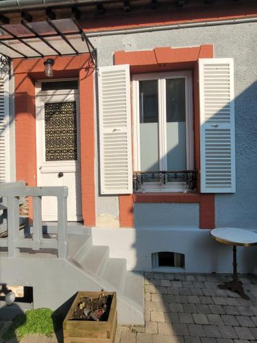 a house with white shutters and a window at La maison de toujours in La Garenne-Colombes