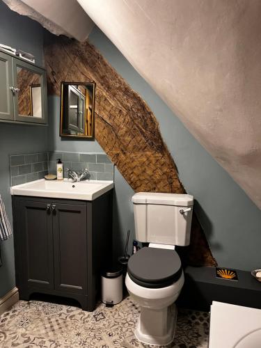 a bathroom with a sink and a toilet and a stairs at Under The Thatch at Rose House in Iwerne Minster