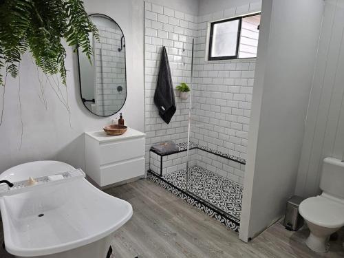 a bathroom with a shower with a toilet and a sink at North Hamptons Retreat in Bundaberg