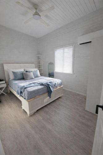 a white bedroom with a bed and a ceiling fan at North Hamptons Retreat in Bundaberg