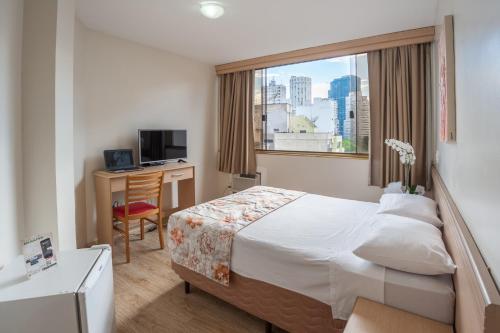um quarto de hotel com uma cama, uma secretária e uma janela em Hotel Dan Inn São Paulo Higienópolis - METRÔ MACKENZIE em São Paulo
